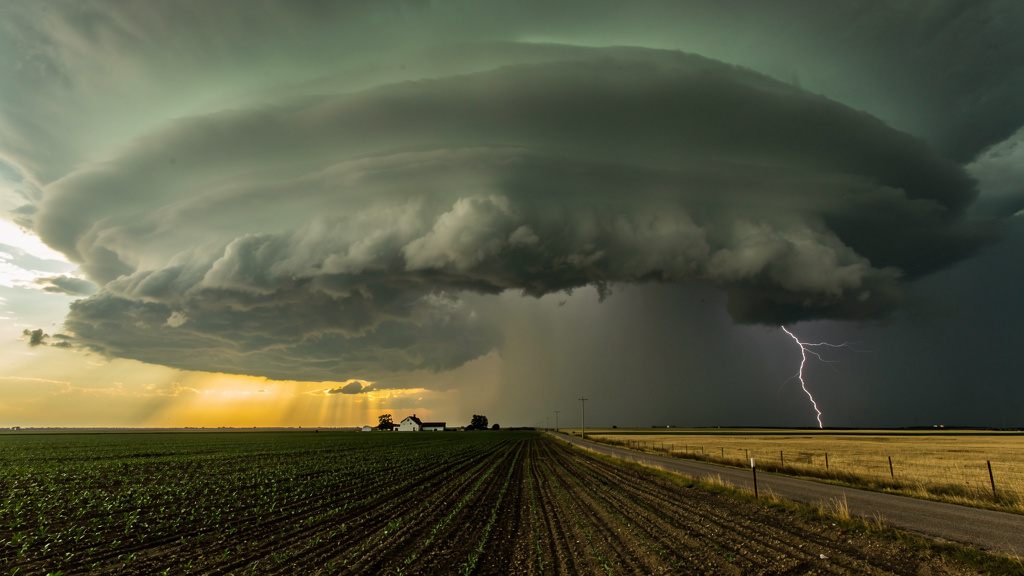 Severe thunderstorm with towering cumulonimbus clouds approaching over a rural landscape with lightning in the distance, representing the spectrum of natural hazards that drive preparedness priorities